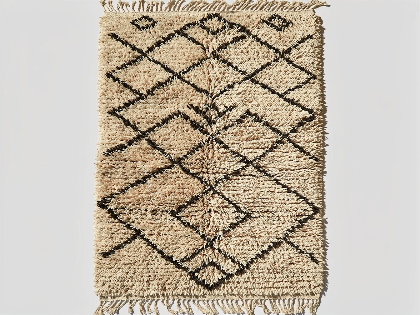 Gros plan sur la laine épaisse et les motifs géométriques noirs d'un tapis Beni Ouarain authentique